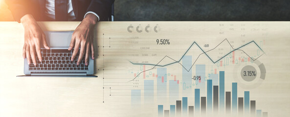 A businessman uses a laptop to analyze financial data, with charts and graphs displayed on the...