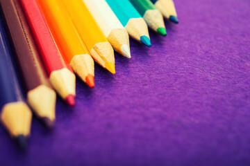 Nine multicolored pencils on a purple felt background. Different colored pencils with space for text. Back to school. Art lessons.