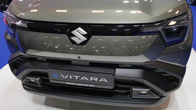 Front mask of modern japanese battery electric compact crossover SUV car Suzuki e Vitara, dark grey chassis color, displayed on car expo in Nitra, Slovakia, october 2025. 