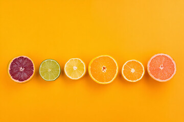 Colorful citrus fruit slice orange grapefruit lemon lime arranged in row on bright yellow background minimal style fresh and vibrant healthy food summer concept top view