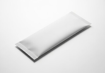 A plain white rectangular sachet or packet lying diagonally on a white background