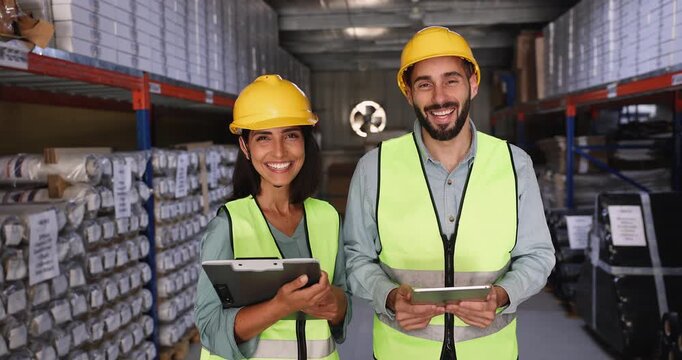 Confident warehouse teammates pose in safety vests and helmets