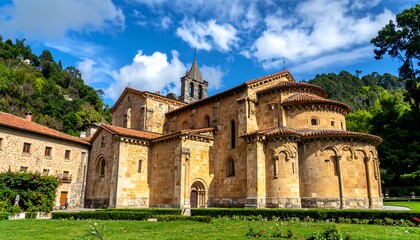 Fototapeta premium A panoramic view of a Romanesque stone church nestled amongst lush greenery, under a vibrant blue sky with puffy white clouds