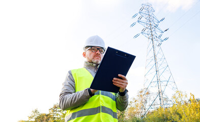 Electrical engineer stands next to power lines. Control electric management.