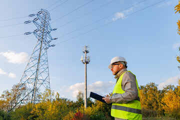 Electrical engineer maintaining power lines against a blue sky. 5G mobile communications control tower. 