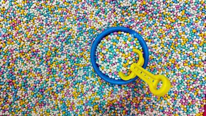 Shovel and bucket full of colourful Sand Pool in a playground. Playground indoors.