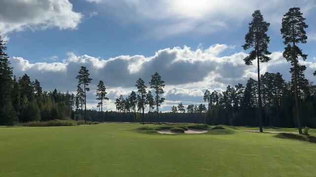 Expansive golf course landscape showcases lush green fairway and sand traps, with trees framing the scene, camera pans across the serene environment