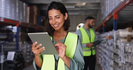 Woman wearing safety vest working in warehouse on tablet - Powered by Adobe