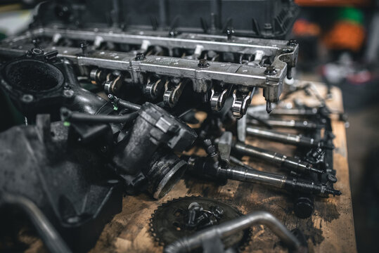 Disassembled engine parts displayed on a wooden workbench, ready for repair or maintenance in a workshop setting.
