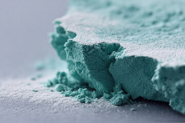 Macro shot of a textured, fractured teal block dusted with white powder. Evokes geology, minerals, or abstract landscapes. Ideal for science, technology, or design concepts.