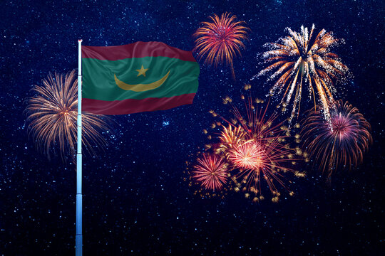 Flags of Mauritania flutters on flagpole in night sky with fireworks