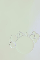 Macro of transparent bubbles of different sizes, floating in water on a very light pastel yellow background. Minimal, clean, vertical composition with copy space; suitable for banners and design
