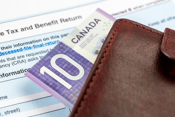 Canada taxes. Income tax and benefit return form and a wallet with a $10 bill. Financial concept. Close up. Selective focus
