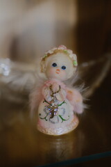 Small angel figurine holds a jeweled cross on a necklace in a display case.