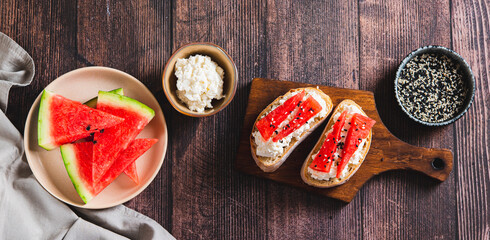 Light crostini with ricotta and watermelon on a board on a table top view web banner