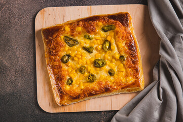 Close up of spicy pizza with jalapeno pepper, corn and cheese on a wooden board top view