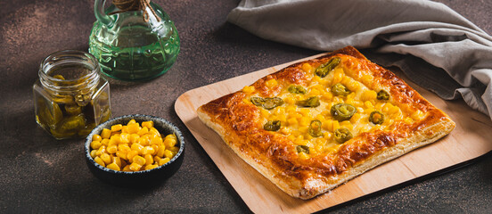Spicy pizza with jalapeno pepper, corn and cheese on a wooden board web banner