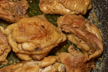 Pieces of chicken meat are fried in a frying pan, exuding flavor and mouth-watering appearance. Delicious chicken pieces are fried in a frying pan until golden brown.