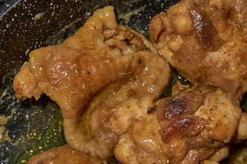 Pieces of chicken meat are fried in a frying pan, exuding flavor and mouth-watering appearance. Delicious chicken pieces are fried in a frying pan until golden brown.