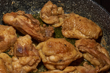 Pieces of chicken meat are fried in a frying pan, exuding flavor and mouth-watering appearance. Delicious chicken pieces are fried in a frying pan until golden brown.