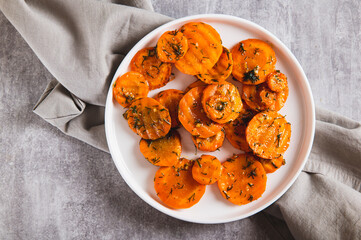 Close up of pieces of fried carrots with garlic and herbs on a plate on the table top view
