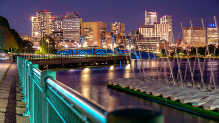 The skyline of Boston in Massachusetts at night as seen from Memorial Driver Road in Cambridge, MA, USA with the famous Charles river in between the two cities.