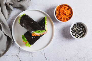 Tuna, cheese, Korean carrots and lettuce wrapped in nori on a plate on the table top view