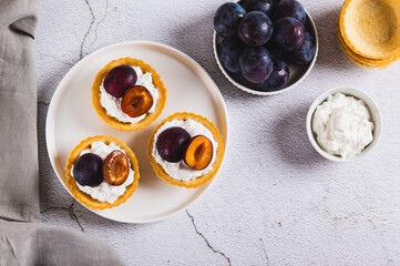 Mini tartlets with cottage cheese and plum on a plate on the table top view
