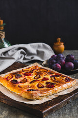Sweet focaccia with plum on a wooden board on the table vertical view