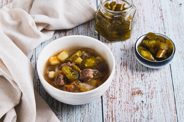 Spicy mexican soup with meat and jalopenos in a bowl on the table
