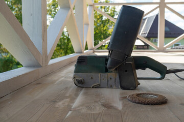 Electric belt sander on wooden deck during home renovation project