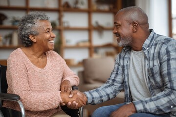 A joyful senior African American woman in a wheelchair shares a friendly handshake with a man in a cozy living room, embodying warmth and connection, perfect for uplifting stories.