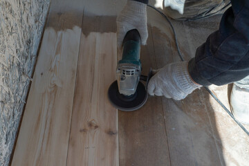 Wood floor sanding with electric sander by gloved worker in workshop © Natasha 