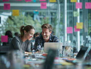 Colleagues collaborate happily on laptop in modern office with colorful notes
