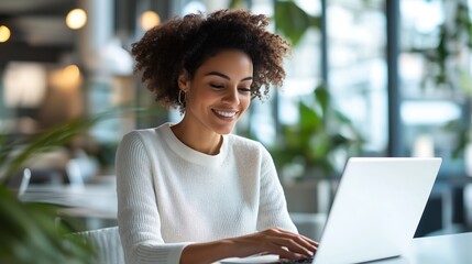 Smiling woman working on laptop in bright modern office, achieving success with ease