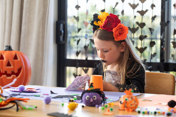 Young girl crafting at halloween themed table with flower crown. Children's crafts for Halloween