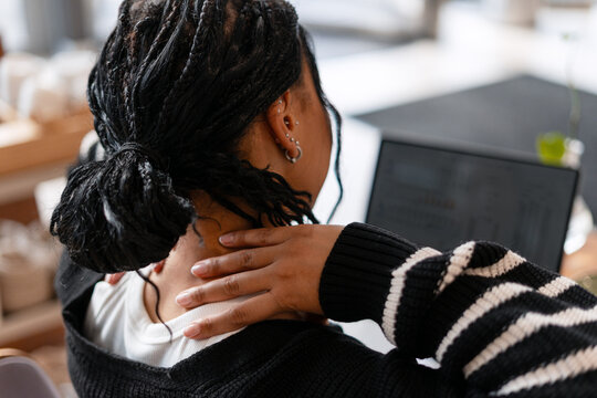 Back view African American woman experiencing neck pain due to office work stress - Powered by Adobe