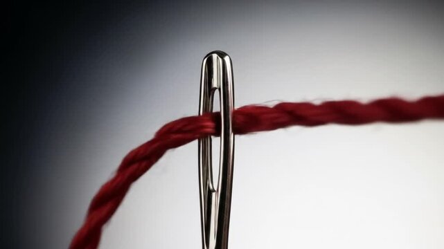 Vibrant red thread glides through the eye of a needle, showcasing precision and artistry in crafting and sewing projects, perfect for creative uses