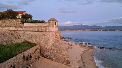 The powerful high walls of the old Corsican fortress on the seashore