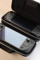 Two portable game consoles in protective cases &mdash; a concept of mobile gaming, traveling with gadgets, and modern tech style.