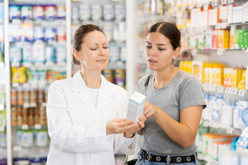 Pharmacist advises customer in a pharmacy, offers medicine for body care