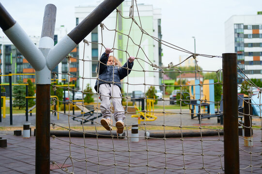 child climbing playground rope net challenges physical abilities and encourages active outdoor adventure. modern urban play area background promotes healthy fitness lifestyle for children