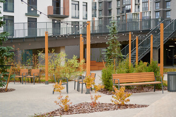 modern urban courtyard with benches and greenery featuring string lights under contemporary residential buildings. ideal for relaxing, socializing, or outdoor gatherings in a communal space