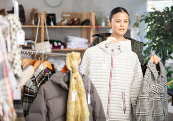 Fototapeta premium Elegance asian young woman choose something for autumn-winter season in modern clothing boutique