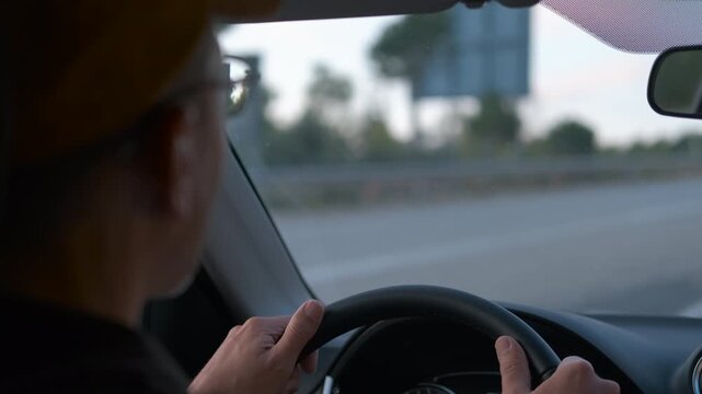 Man driving car on highway, changing lanes and overtaking. Senior man wearing glasses is driving a modern car on a highway, changing lanes, overtaking other vehicles and adjusting the steering wheel