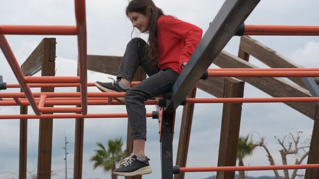 Young girl climbing monkey bars at playground. Child navigating monkey bars with confident movement, displaying joyful energy while developing physical coordination and playground skills