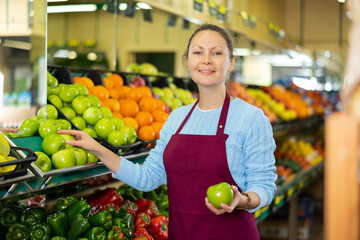 friendly woman seller chooses ripe and juicy apples for buyer