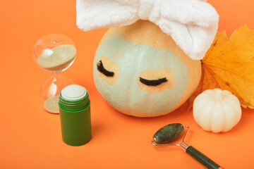 Skin care season concept, pumpkin and cosmetics on orange background, mock up