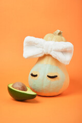 Pumpkin and avocado on an orange background, beauty treatments for autumn skin care, copy space, mock up