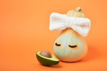 Pumpkin and avocado on an orange background, beauty treatments for autumn skin care, copy space, mock up
